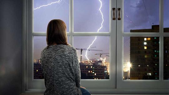 Frau sieht aus dem Fenster bei Unwetter